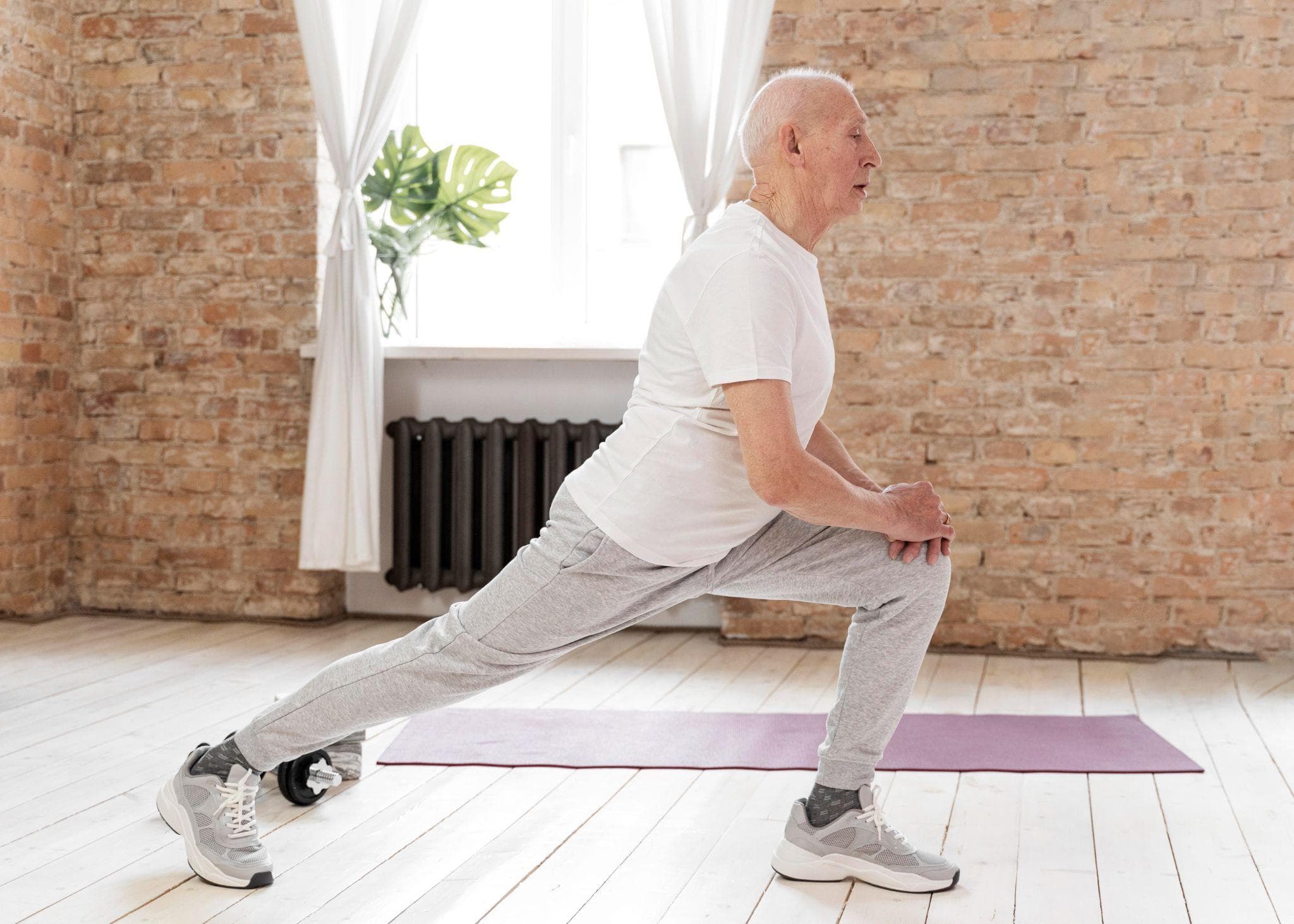 An old man is exercising and stretching in his house.