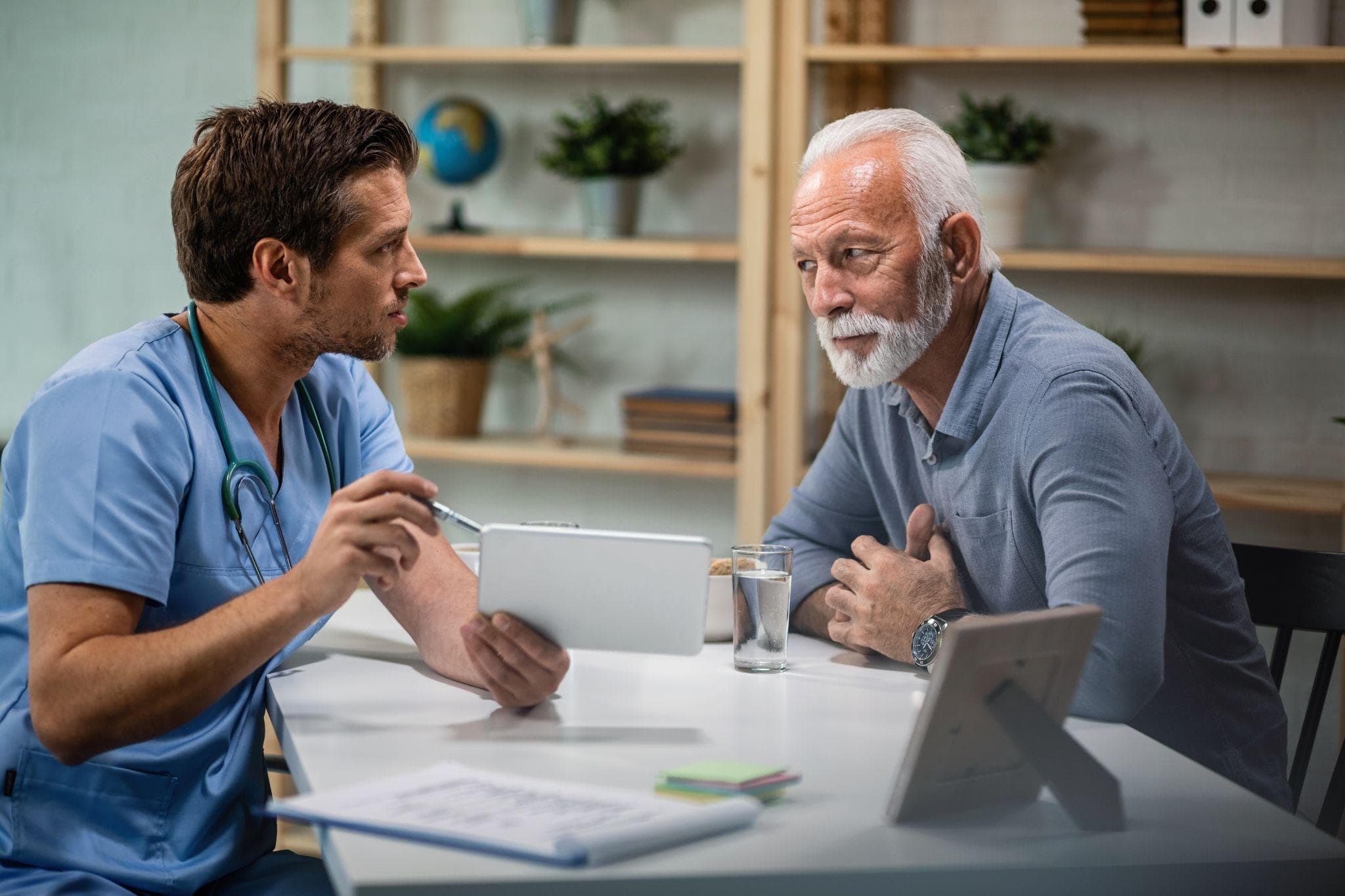 A male doctor is consulting with his patient, who is an old man in his clinic.