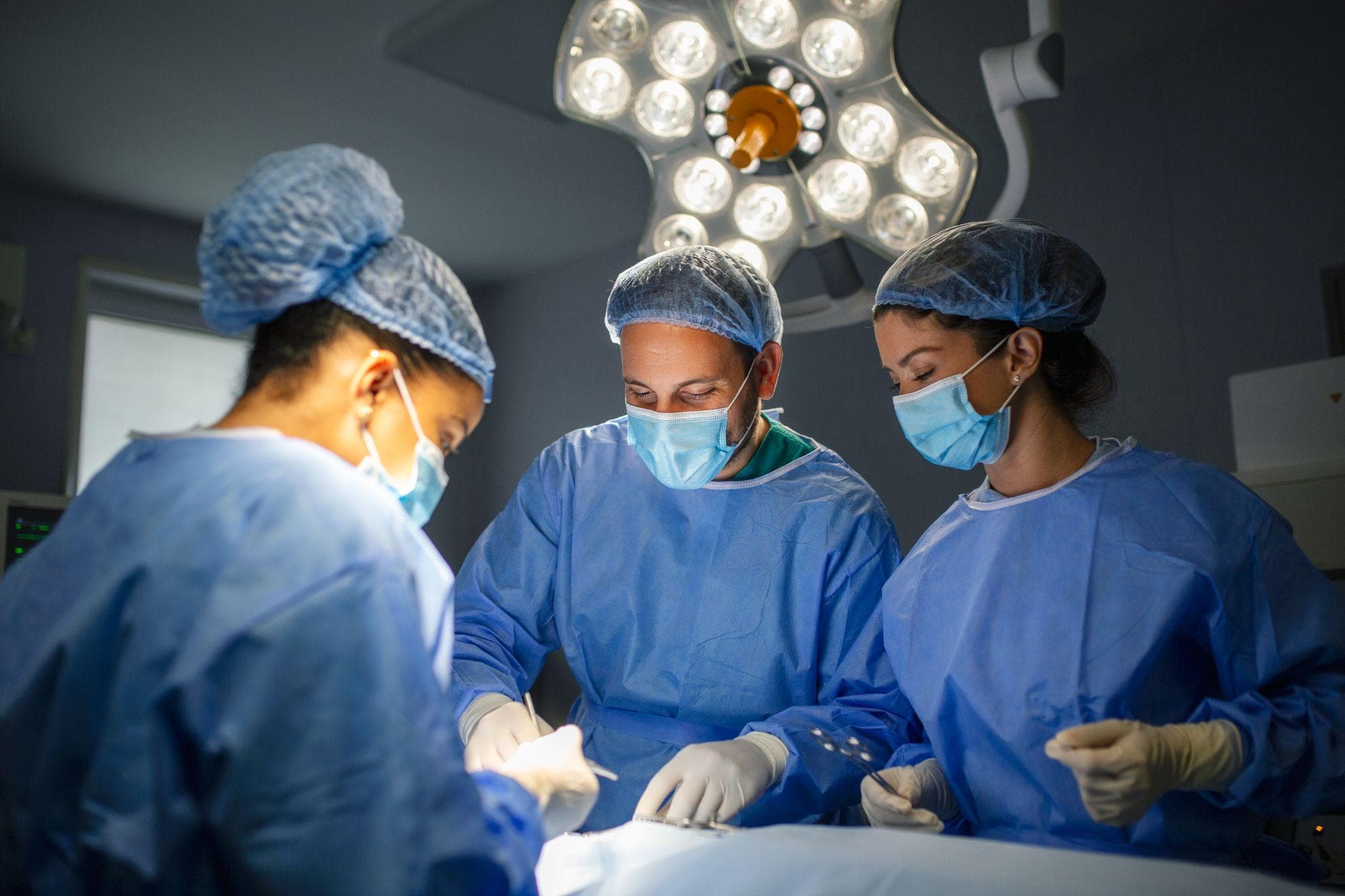 A team of surgeons is operating on a patient lying down in their operating room.