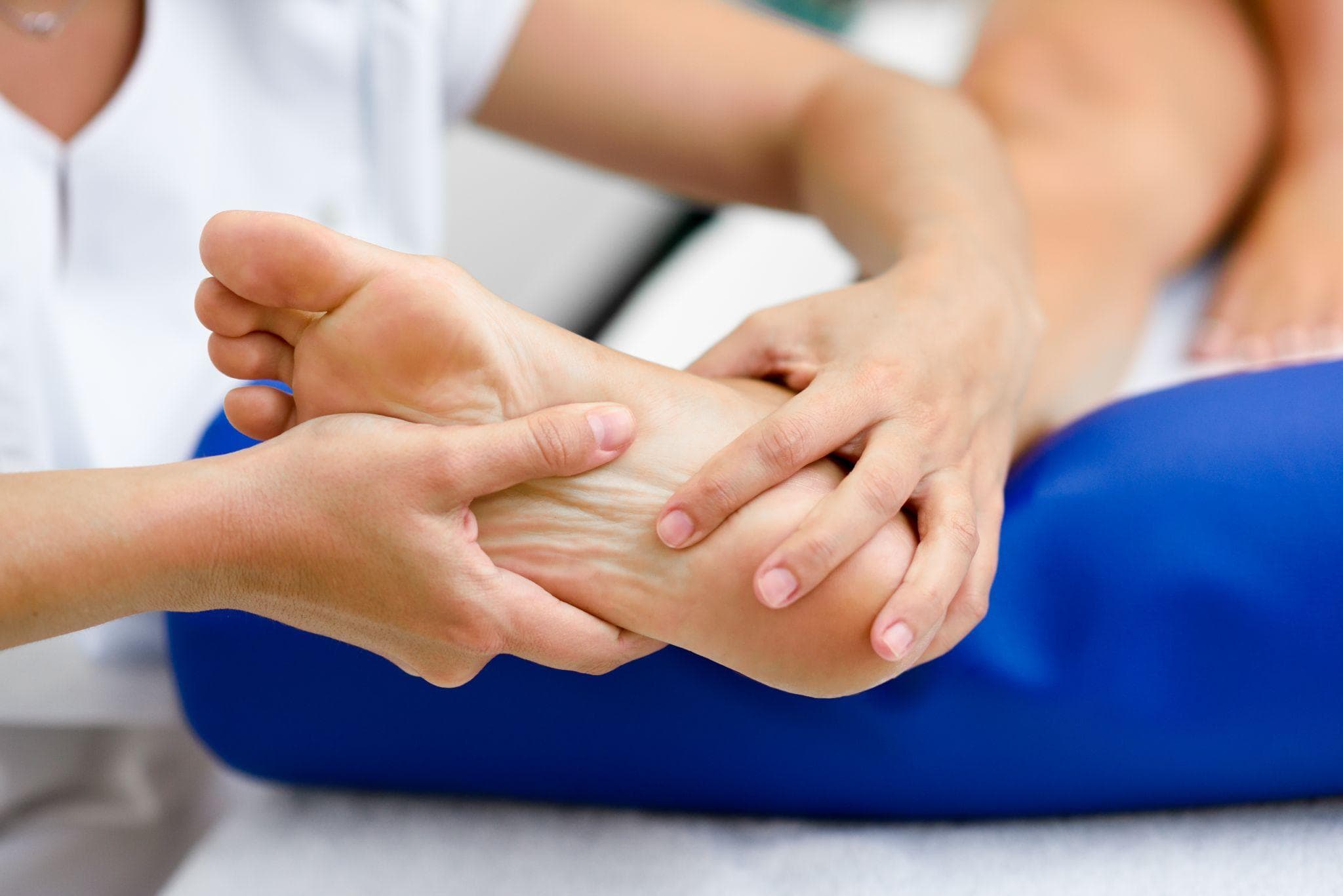 A doctor is doing physiotherapy on the back of the heels of the patient's feet in the clinic.