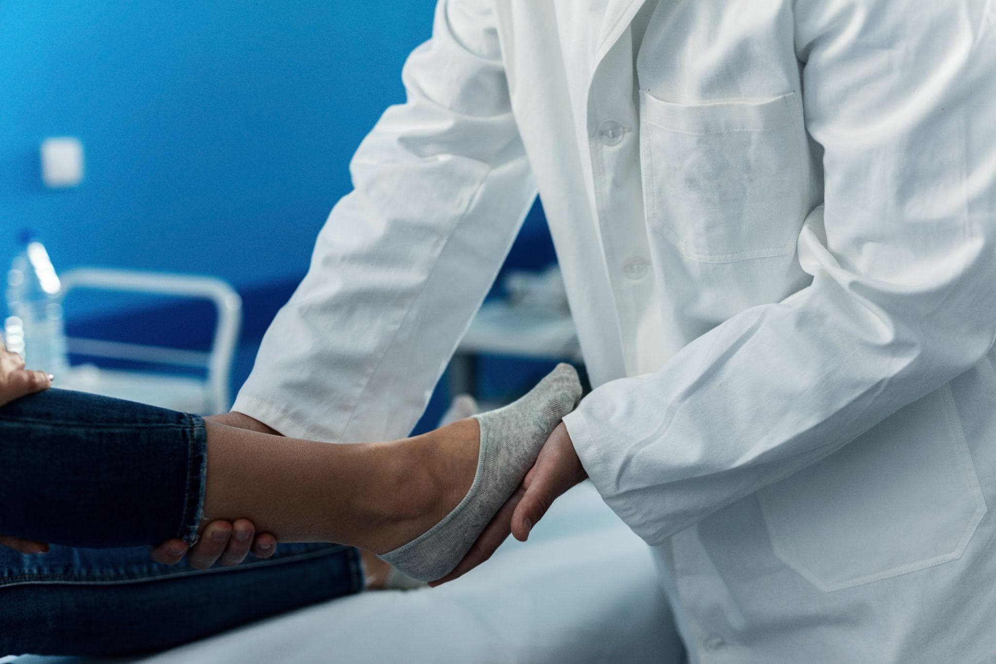 An orthopedic doctor is examining the feet of a patient in the clinic.