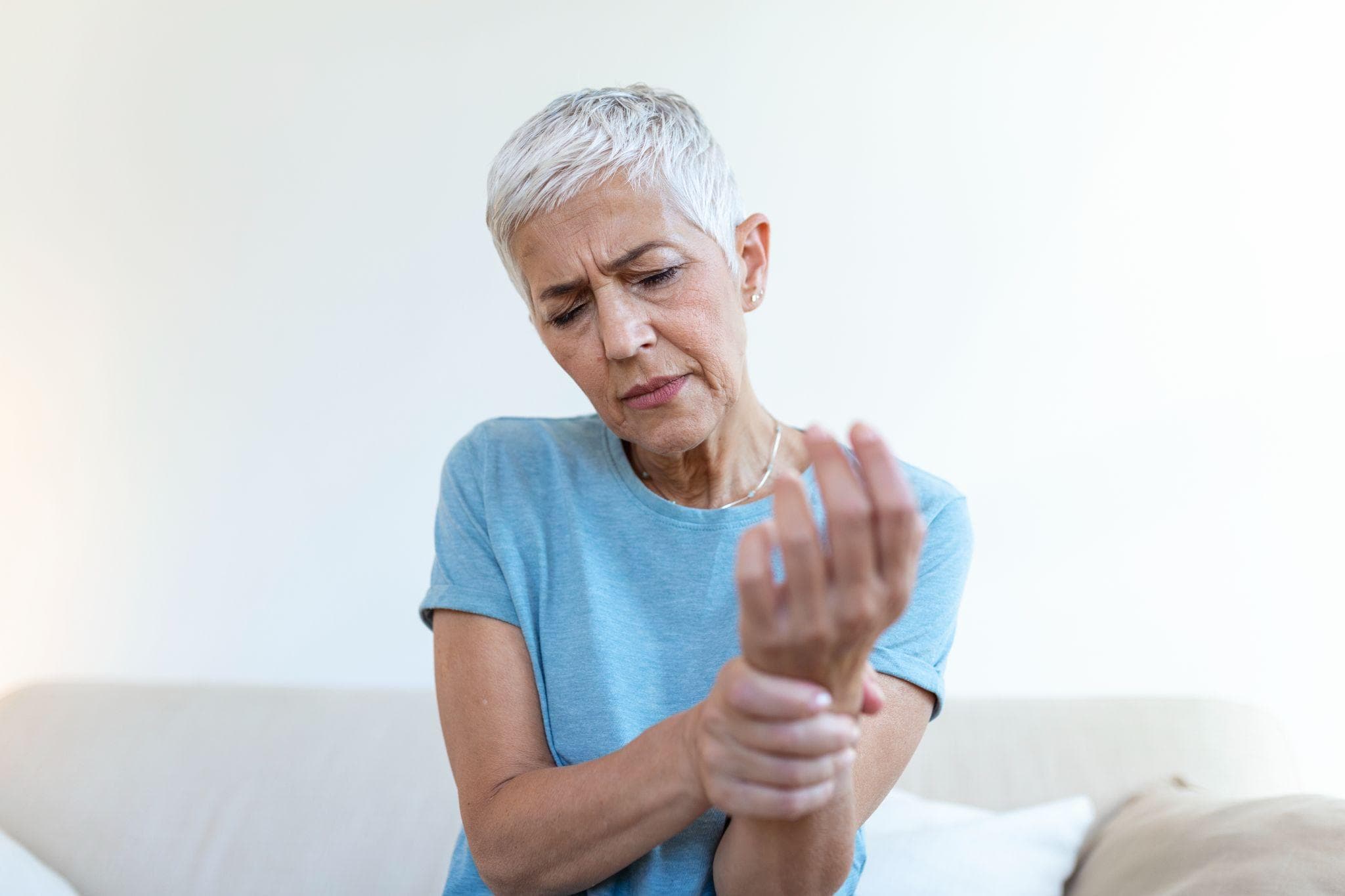 Elderly woman suffering from hand pain at home.