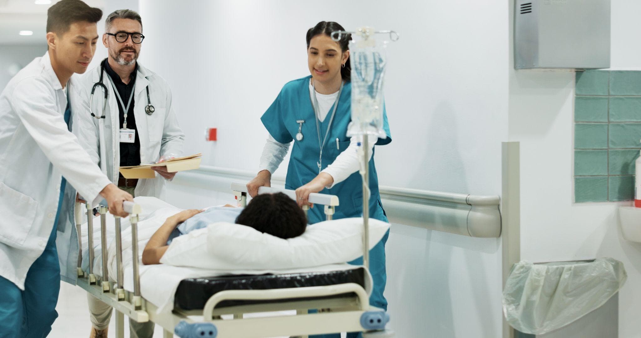 A doctor and nurses are consulting with each other while taking the patient lying on the bed, somewhere else in the hospital.