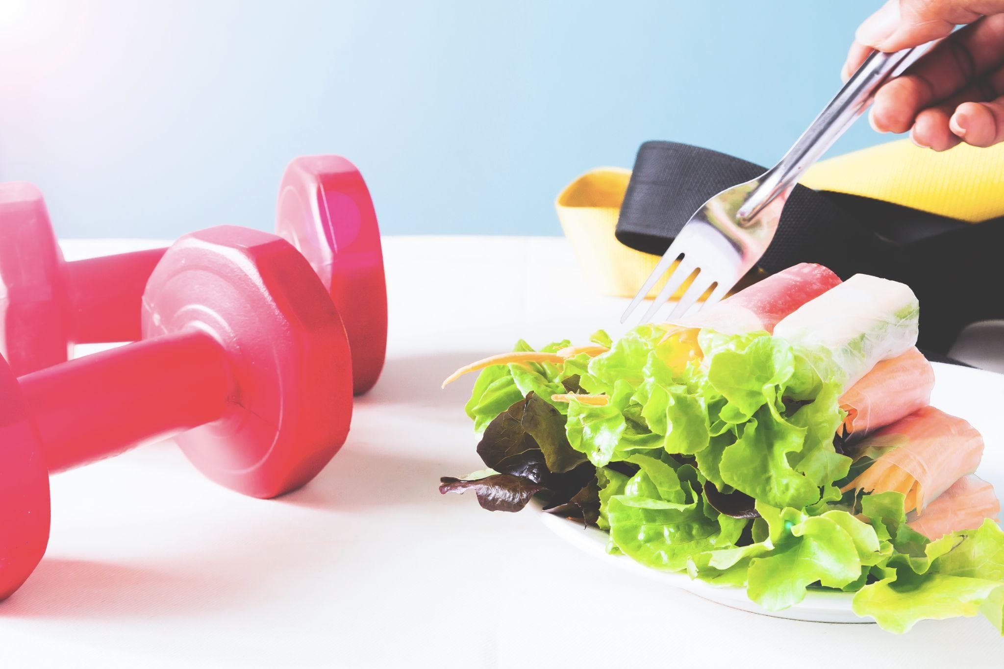 Healthy vegetable salad rolls with dumbbells and a resistance band symbolizing fitness and nutrition.