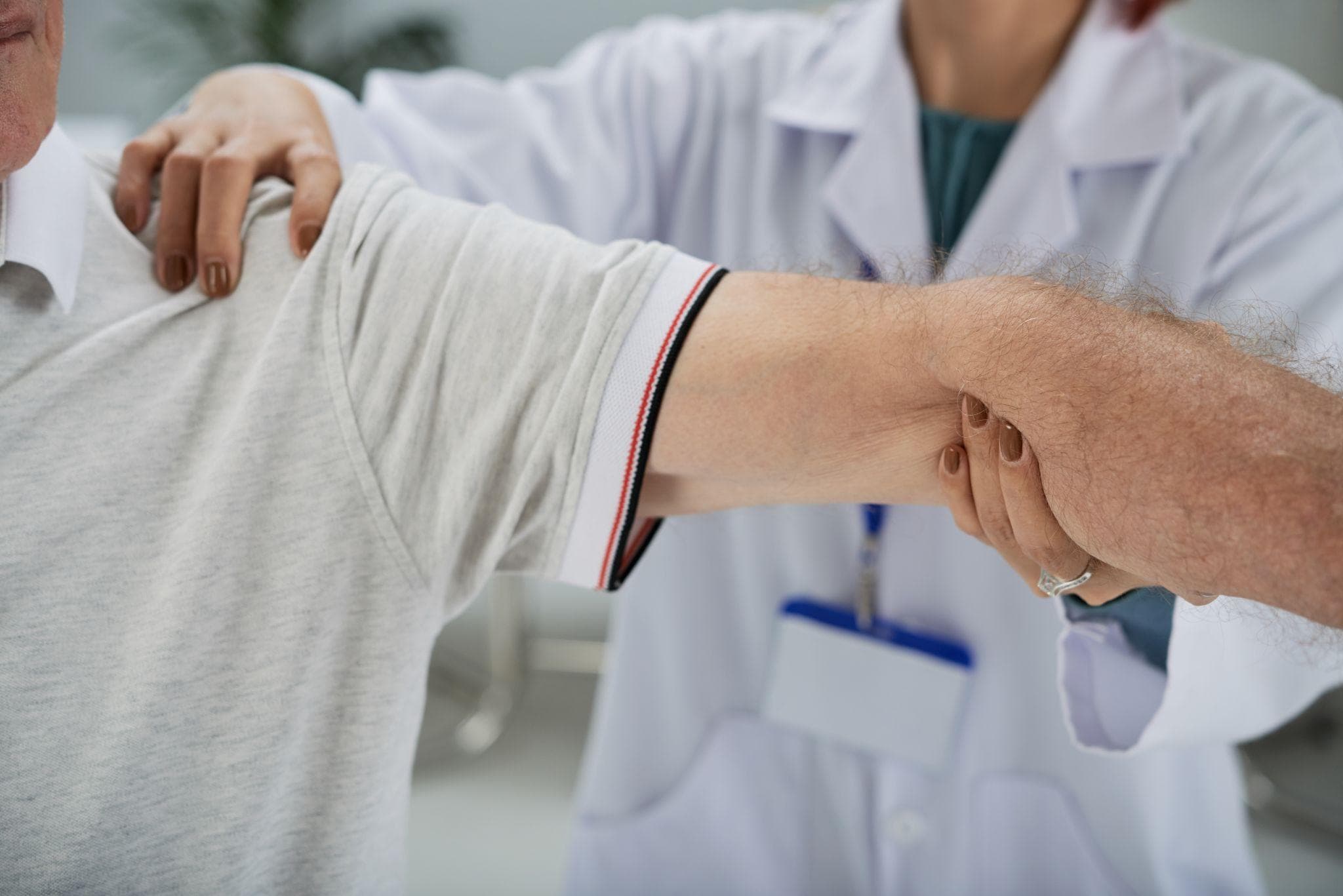 Orthopedic doctor examining a male patient’s shoulder joint in the clinic.