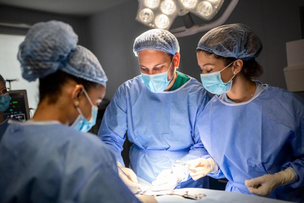 In an operating room, a patient is lying, and surgery is being performed by a group of surgeons with modern equipment.