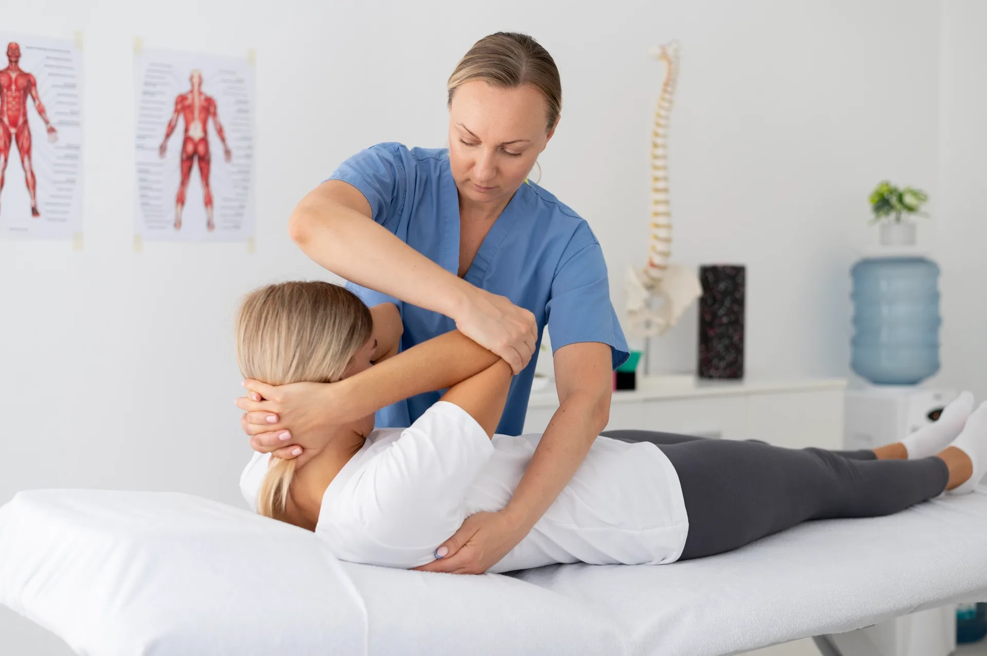 A woman in a physiotherapy session, guided by a therapist who helps her perform controlled exercises or stretches.
