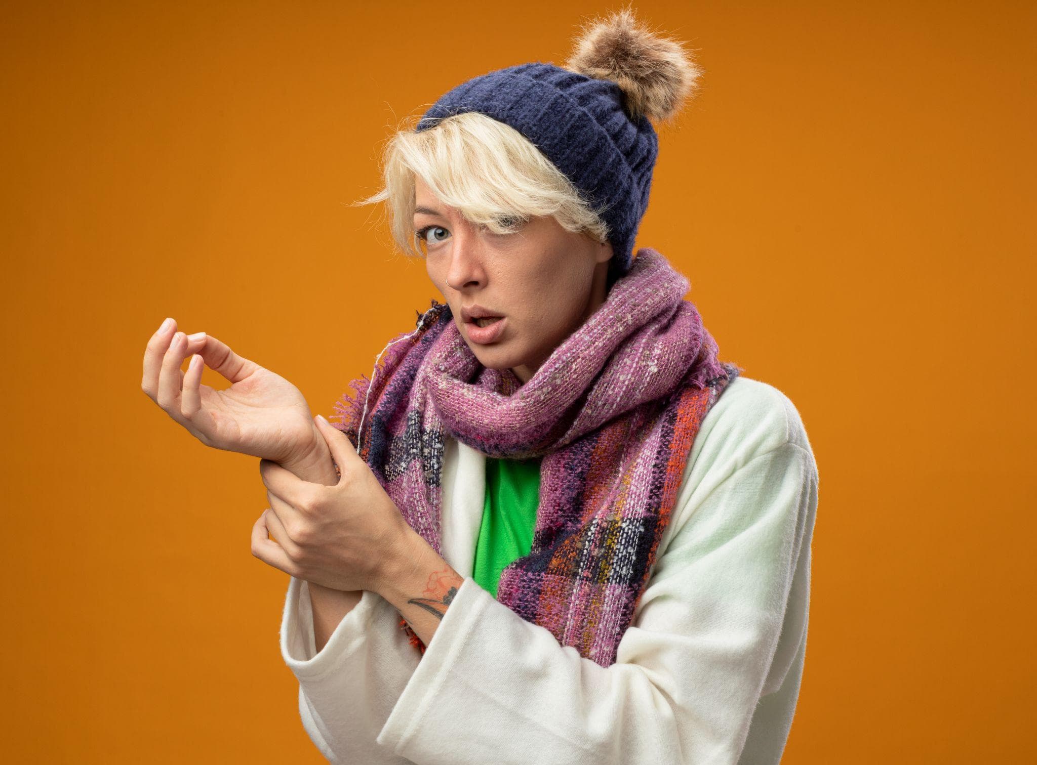 A woman wearing winter clothing showing joint stiffness and wrist pain.