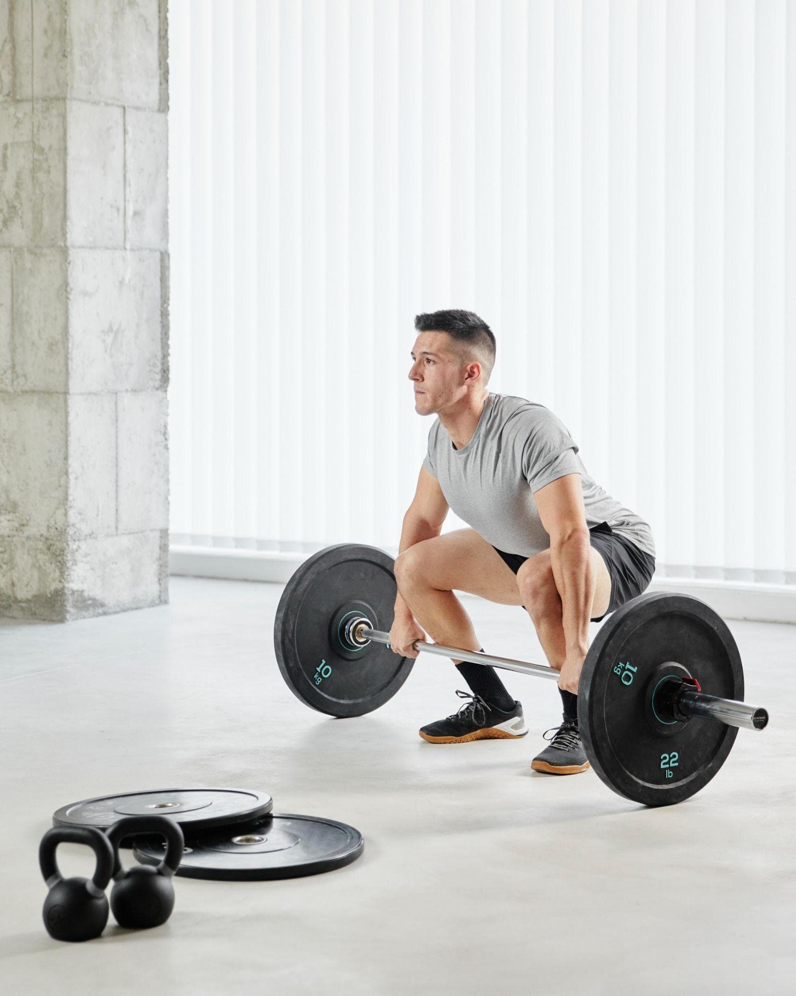 An athlete executes a deadlift with controlled knee bend and proper hip hinge in an indoor gym.
